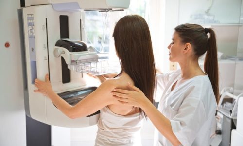 Female doctor and mid adult woman during Mammography test in examination room.